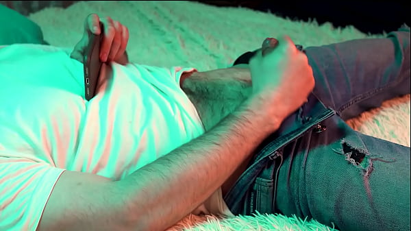 A young hot guy watches porn on his phone and j...