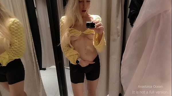 Pervert girl trying on clothes in fitting room with open curtain. People are passing and see her.