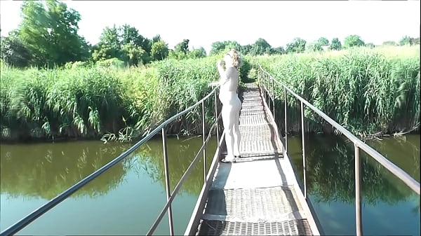 Summer nostalgia. Dressed in sun. Sexy naked woman MILF walks on hanging bridge of river. Nudists. Naturists. Nude beach. Music erotic clip.