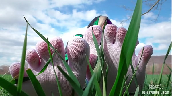 Goddess feet in cute white socks with jeans on the spring grass field