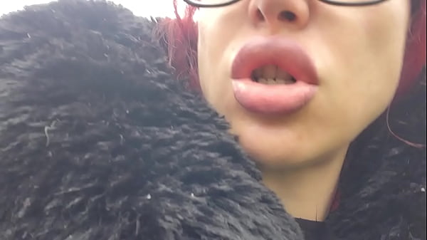 "A red-haired woman with full lips sits on a park bench, letting out loud burps without a care in the world