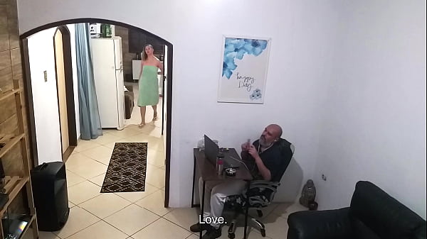 While the husband works, the wife in a towel greets the delivery man.