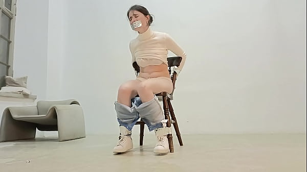 The brunette is tied to a chair with duct tape, her mouth is gagged, her jeans are pulled down