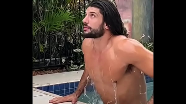 Horny bearded man with long hair getting out of the pool with a full suitcase.
