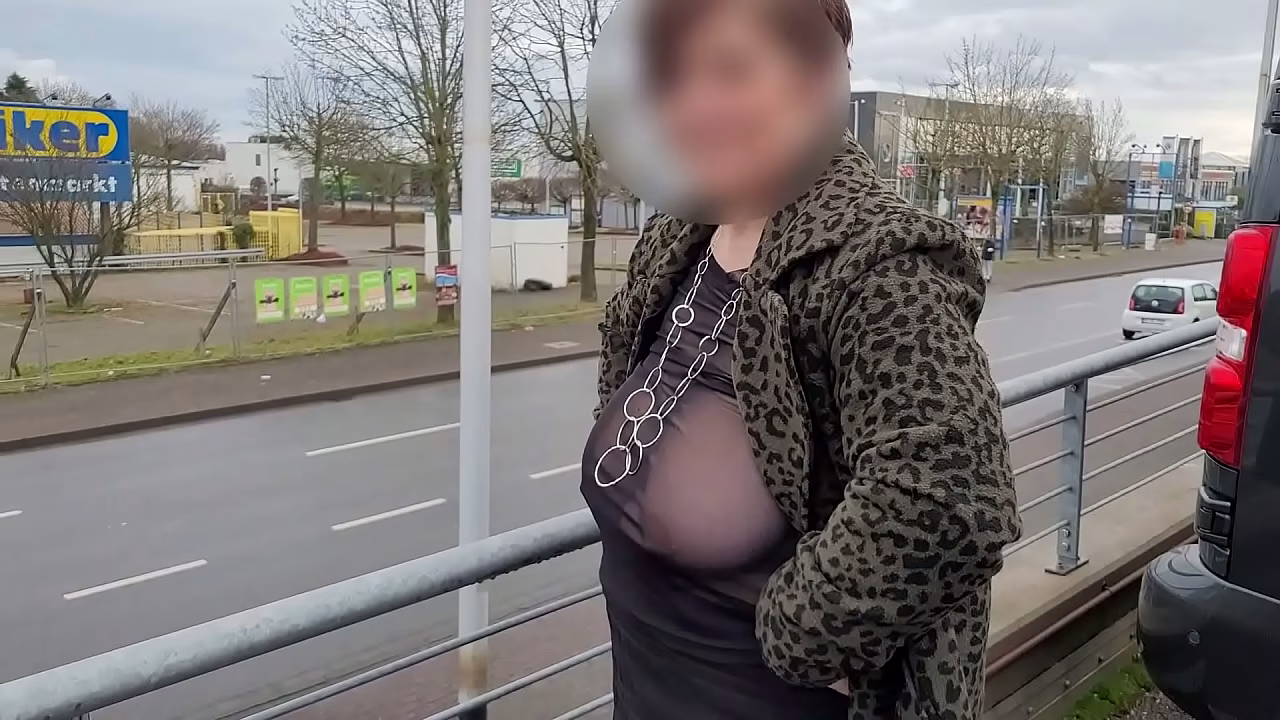 A milf with a sheer top exposed her big tits in the street.