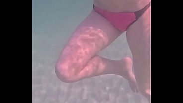アマチュアの長脚で完璧な体型の女の子がリラックスして水中で泳ぐ