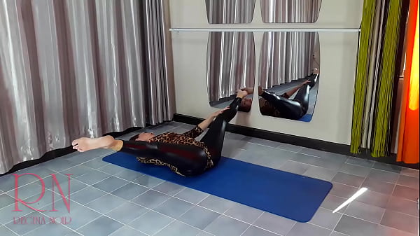 Regina Noir. A woman in a leopard bodysuit and latex leggings is doing yoga in the gym. Yoga in sexy leotards. 1
