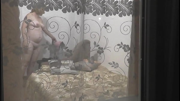 Peeping through windows. Voyeur. In evening, on street random passerby guy looking into bedroom window and filming on camera smartphone as sexy blonde MILF undresses, goes to bed, masturbates pussy, gets strong wet orgasm. Outdoors Outside