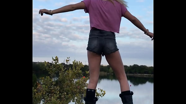 Gorgeous Blonde model with tiny shorts with perfect ass posing for pictures on a rock overlooking the lake