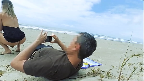 Vacationers look on with disapproval as a milf with her BF films anal content right on the beach